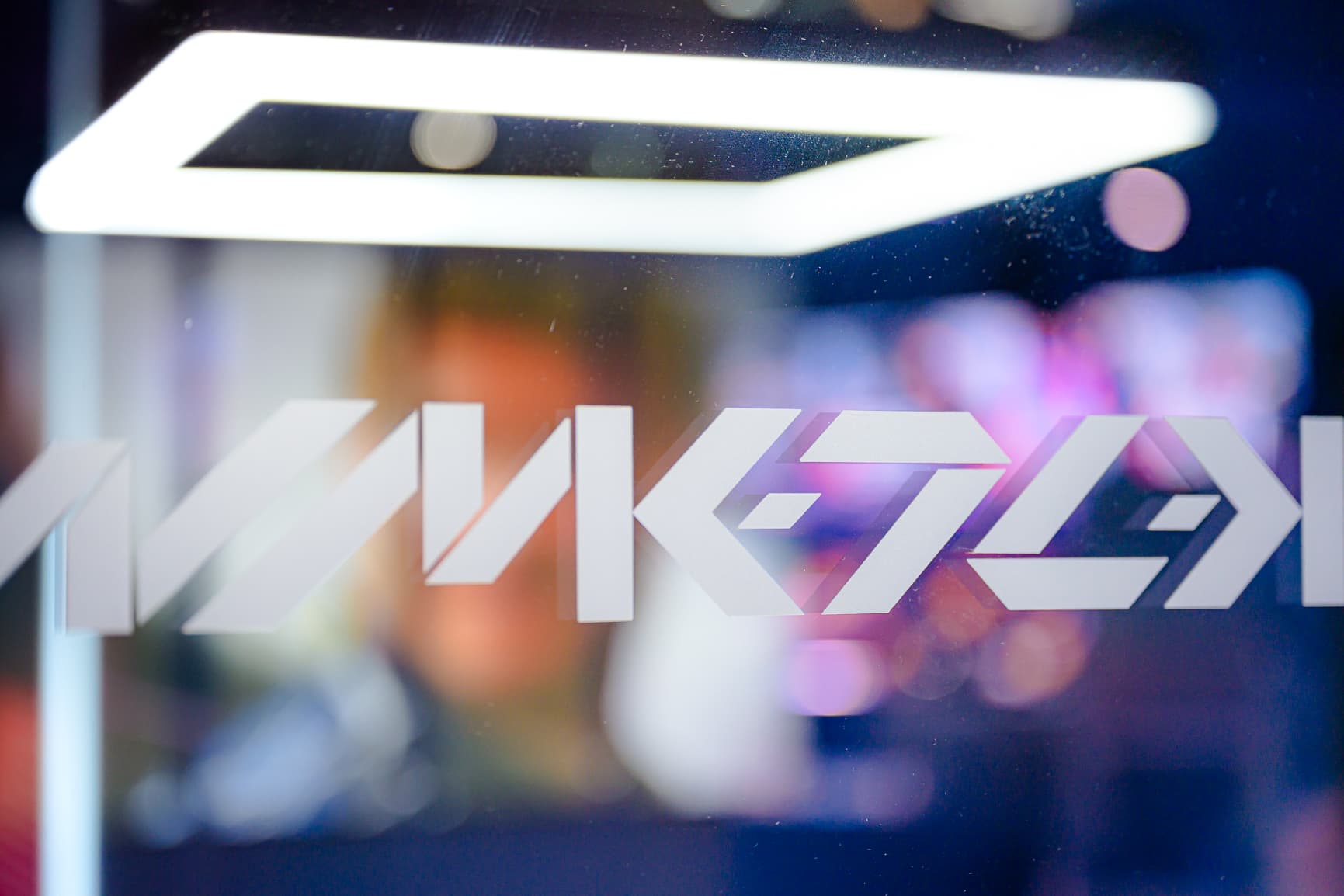 Abstract geometric patterns and shapes on a glass surface with a blurred background and bright lights.