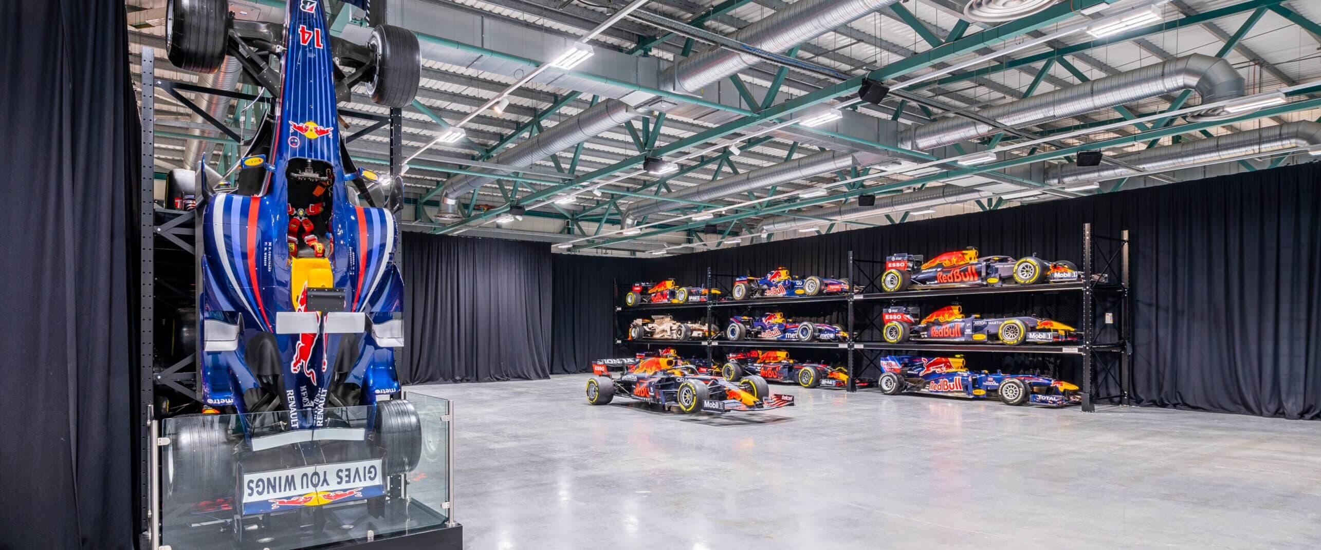 Display of multiple Formula 1 cars in a showroom with a focus on one vertically positioned car in the foreground.